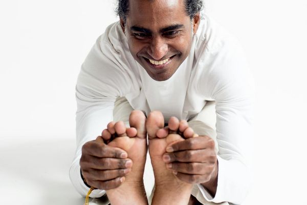 Person in a calm, focused stretching pose in a minimalist room.
